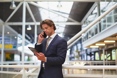 businessman-using-digital-tablet-while-talking-mobile-phone